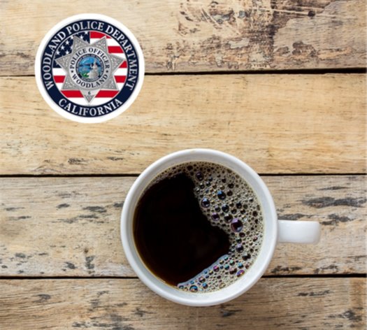Photo of a coffee mug on a wooden table with the Woodland Police Department roundel at top left