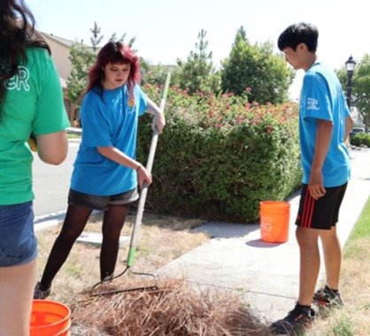 Photo of three teens raking foliage in past program