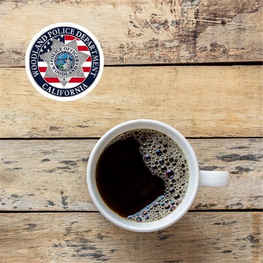 Image of a cup of coffee on a table with the Woodland Police Department roundel logo at the upper left