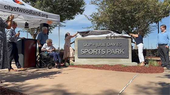 Photo of two people unveiling a monument sign reading "Skip + Julie Davies Sports Park"