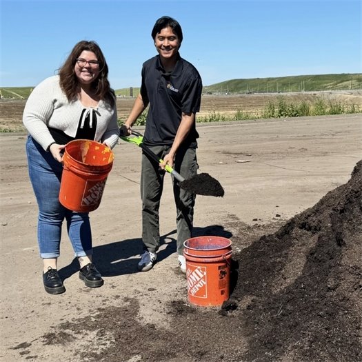 Image of two individuals shoveling compost