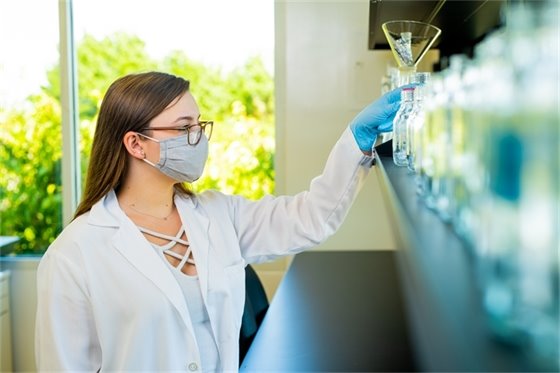 Image of scientist reaching for beaker in the Lab at AgStart