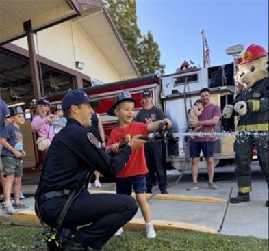 Photo of a firefighter and a young person operating a fire hose
