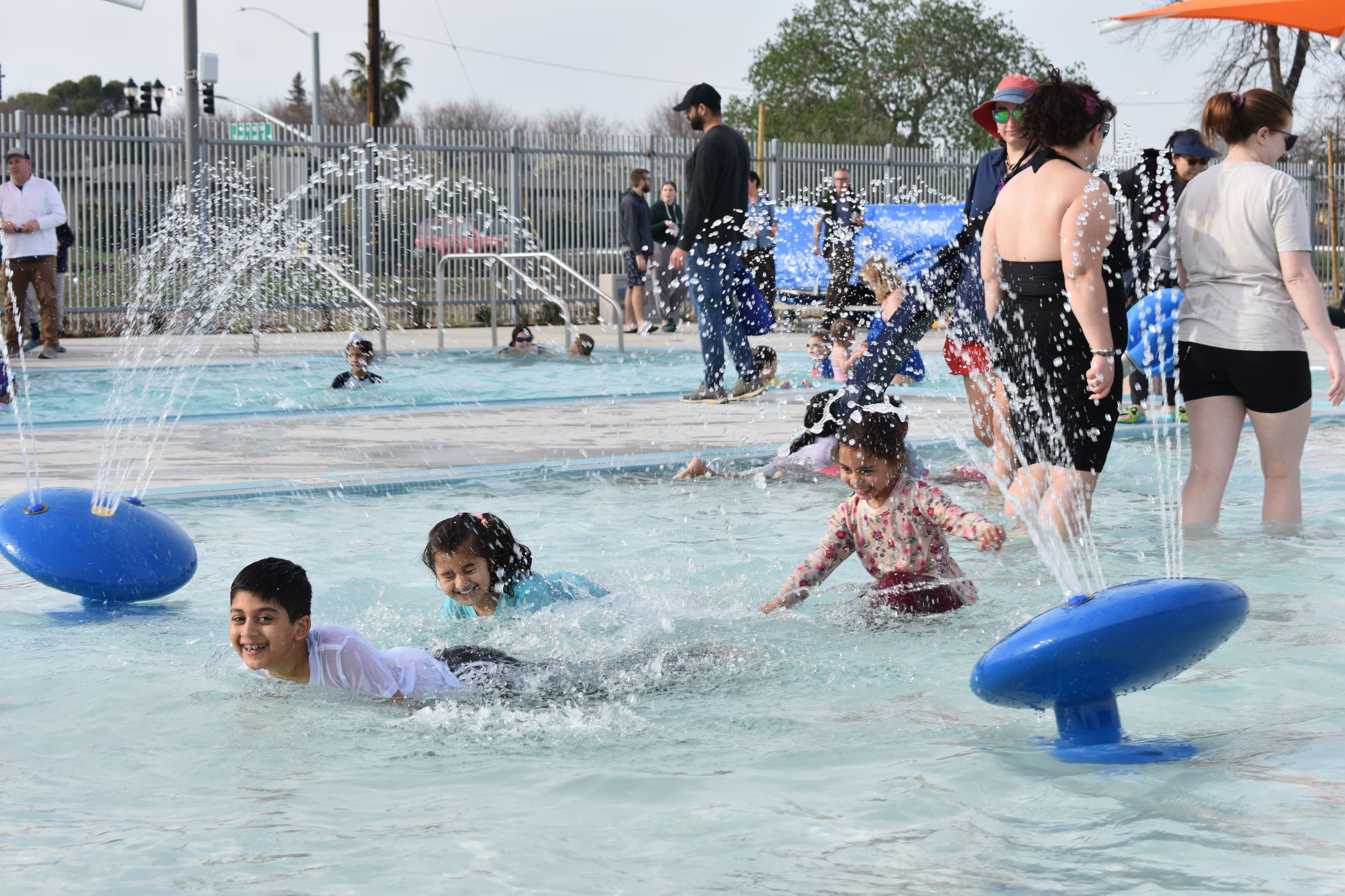 Children playing in pool with water play features shooting water